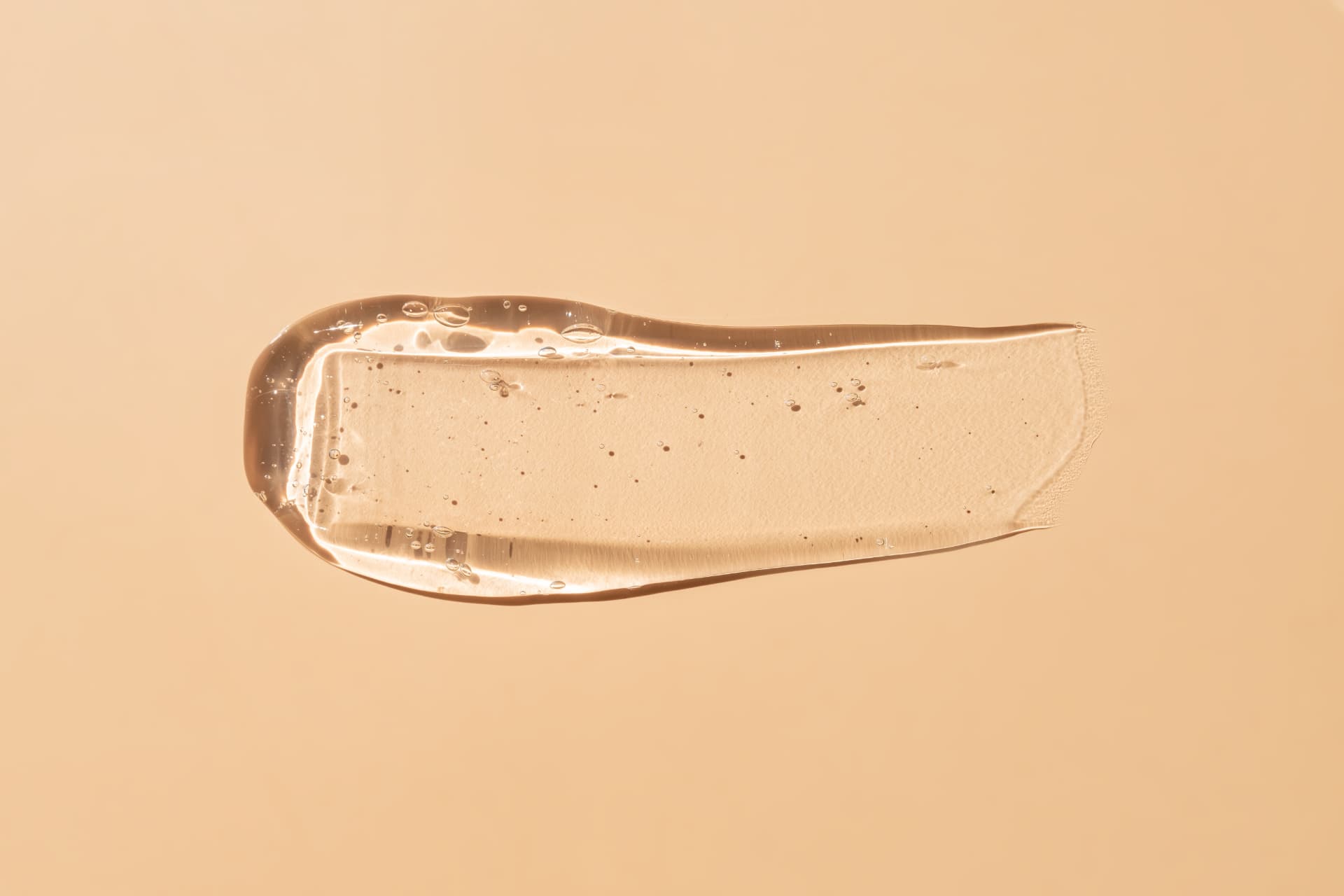 Clear treatment gel swatch smeared across a warm beige surface